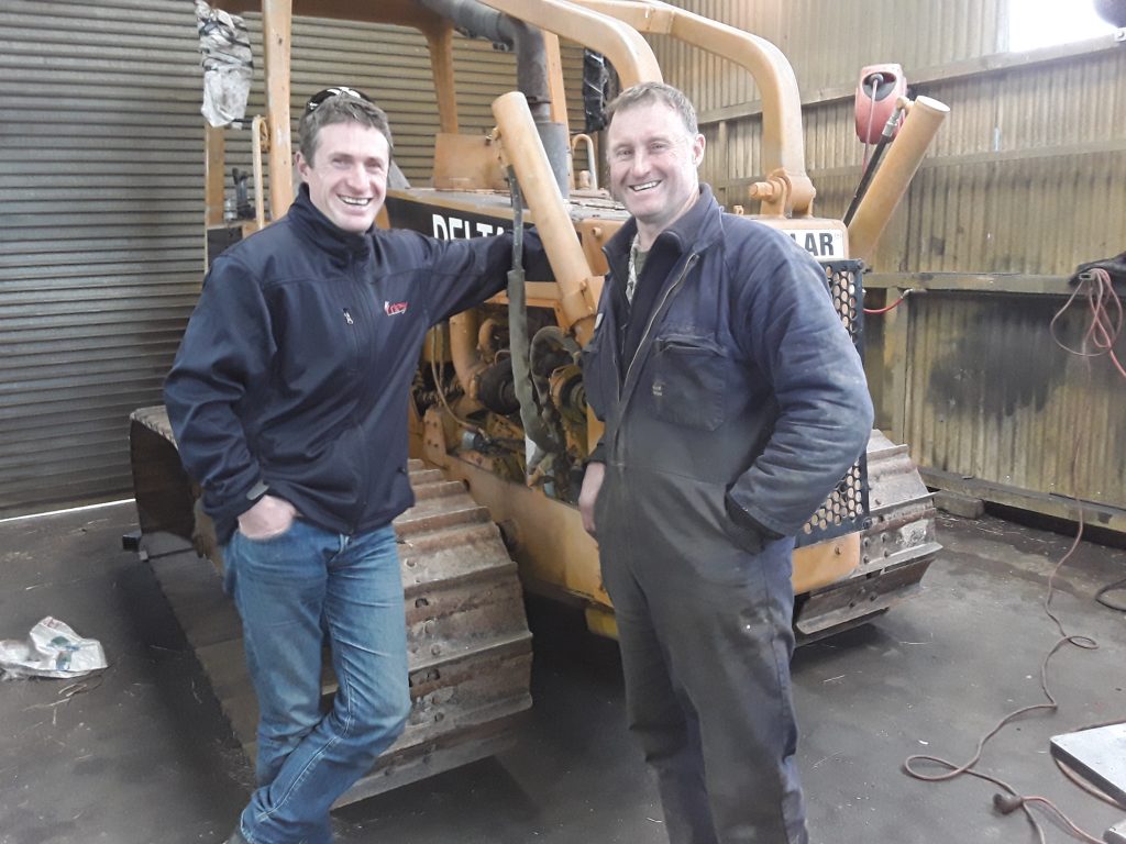 Joe Stringer in front of customer Mike Key from James Engineering with the bulldozer being modified to lay fibre.